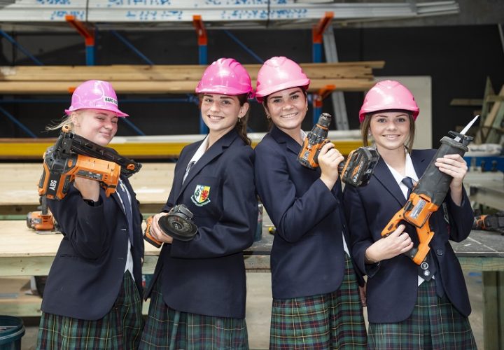 Four female school students holding trade tools